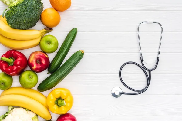 Vista superior de frutas frescas com legumes e estetoscópio na superfície de madeira — Fotografia de Stock