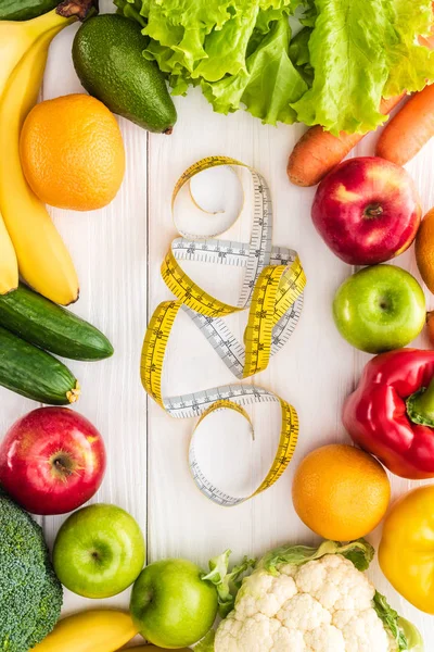 Top view of fresh fruits and vegetables and measuring tape on wooden table — Stock Photo