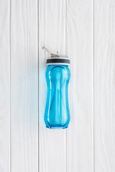 Vista superior de la botella de deportes azul con agua en la mesa de madera blanca - foto de stock