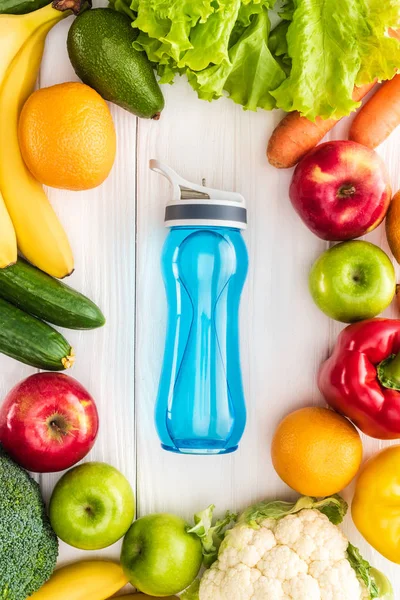 Top view of sports bottle with water and fresh fruits with vegetables on wooden table — Stock Photo