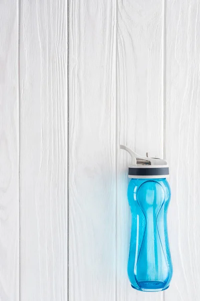 Vista superior de la botella de deportes azul con agua en la mesa de madera blanca - foto de stock