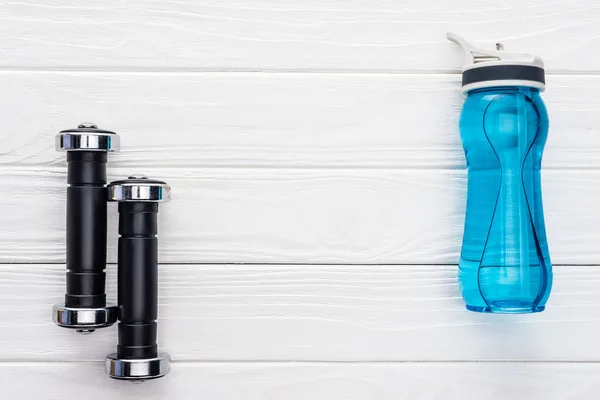 Top view of dumbbells and bottle of water on wooden surface — Stock Photo