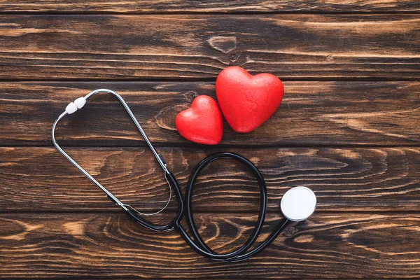 Вид зверху на стетоскоп і червоні серця символ на дерев'яному столі — стокове фото