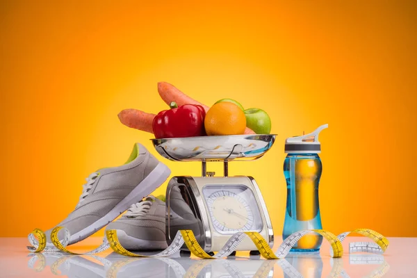 Close-up view of fresh fruits and vegetables on scales, sports bottle with water, sneakers and measuring tape on yellow — Stock Photo
