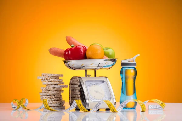 Vista close-up de frutas e legumes frescos em escalas, garrafa de esportes com água e fita métrica em amarelo — Fotografia de Stock