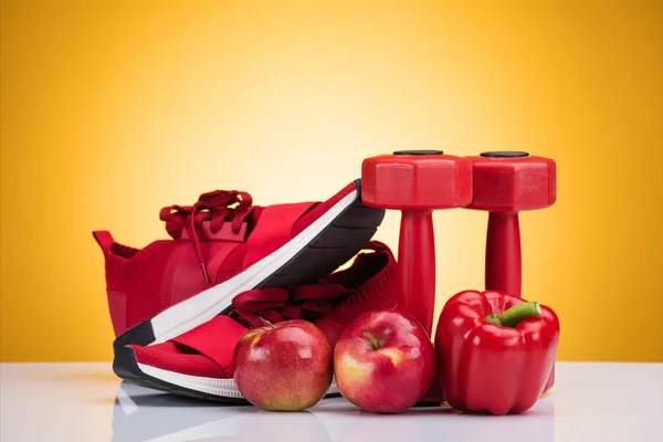 Close-up view of red sneakers, apples, pepper and dumbbells on yellow — Stock Photo