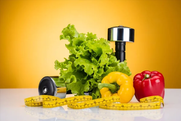 Close-up view of fresh vegetables, measuring tape and dumbbells on yellow — Stock Photo
