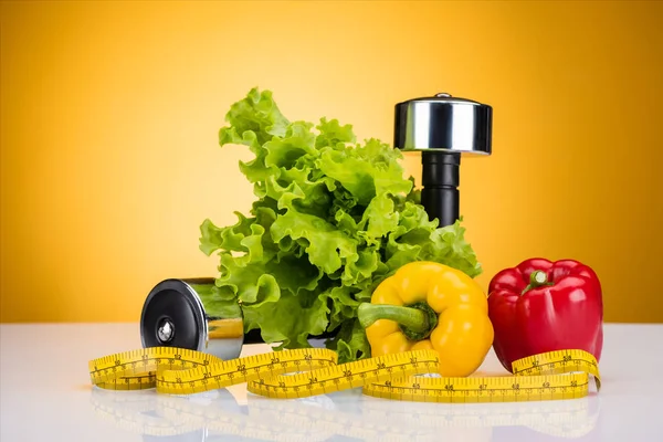 Vista close-up de vegetais frescos, fita métrica e halteres em amarelo — Fotografia de Stock