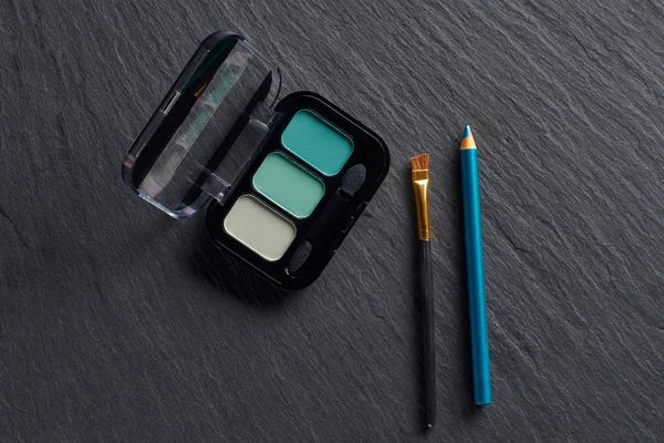 Eye shadows in blue tones with pencil and brush on dark slate background — Stock Photo