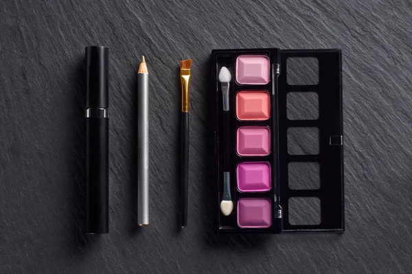 Makeup set with eye shadows, pencil and mascara on dark slate background — Stock Photo