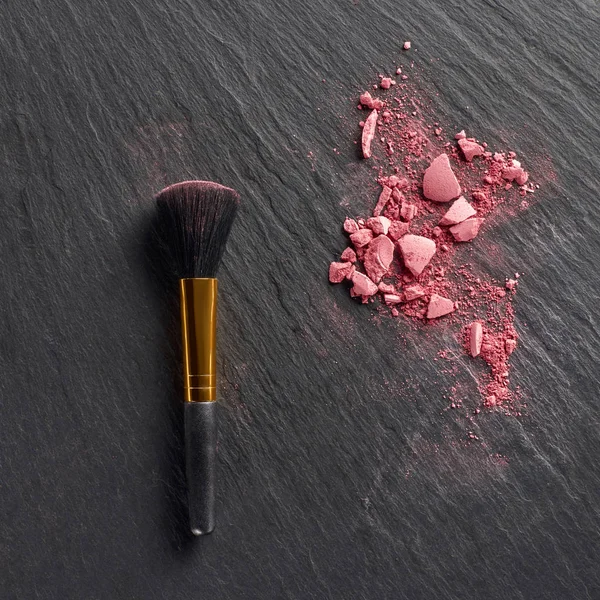 Pedaços de blush rosa e escova no fundo de ardósia escuro — Fotografia de Stock