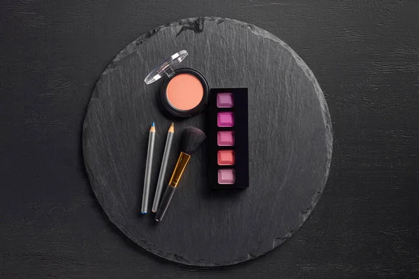 Makeup set with brush on round slate background — Stock Photo