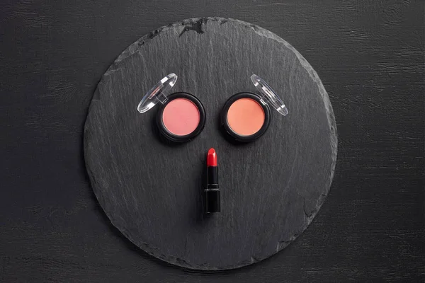 Set of blush and lipstick on round slate background — Stock Photo