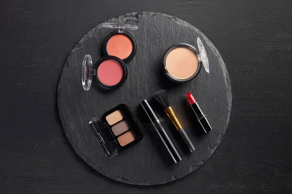 Set de maquillage avec ombres à paupières et fard à joues sur fond d'ardoise ronde — Photo de stock