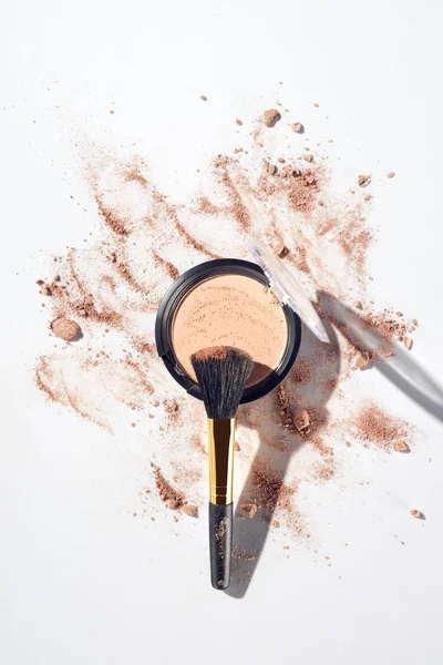 Broken and pressed face powder with brush on white background — Stock Photo