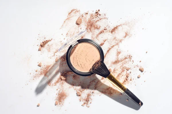 Pressed powder and makeup brush on white background with scattered foundation — Stock Photo