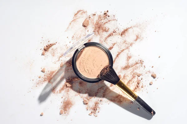 Polvere pressata e pennello per il trucco su sfondo bianco con fondotinta sparsa — Foto stock