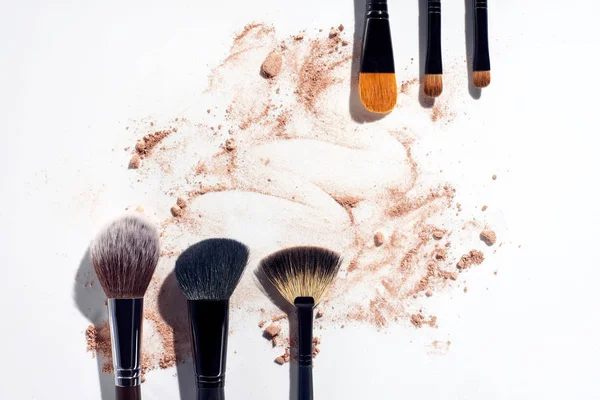 Rahmen aus Make-up-Pinseln mit Puder-Fundament auf weißem Hintergrund — Stockfoto