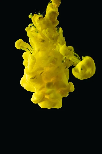 Bright yellow flowing paint explosion on black background — Stock Photo
