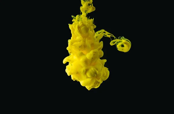 Vista de cerca de la tinta que fluye de color amarillo brillante sobre fondo negro - foto de stock