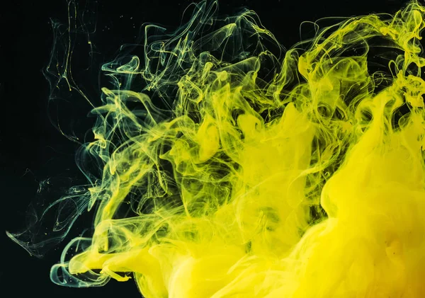 Vista de cerca de pintura fluida de color amarillo brillante sobre fondo negro - foto de stock