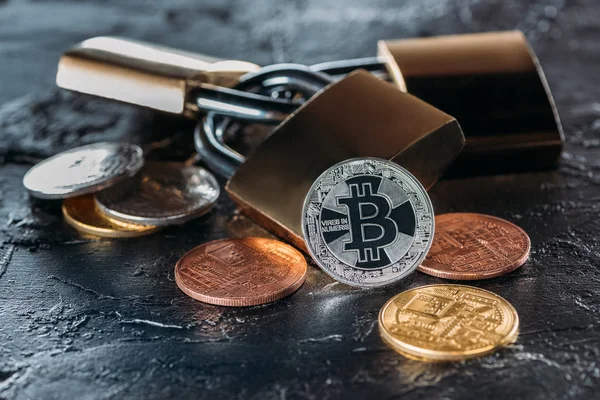 Close up view of arranged locks and various bitcoins on dark surface — Stock Photo