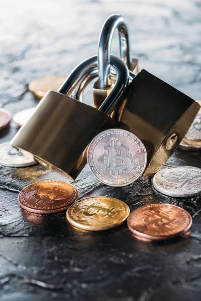 Vue rapprochée des serrures disposées et divers bitcoins sur la surface sombre — Photo de stock