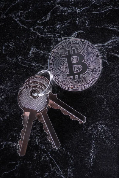 Vista superior de las llaves arregladas y bitcoin de plata en la mesa de mármol oscuro - foto de stock