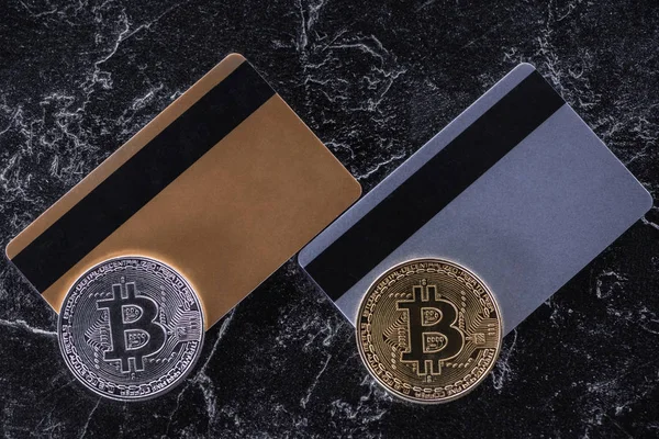 Vista superior de tarjetas de crédito y bitcoins en la superficie de mármol oscuro - foto de stock