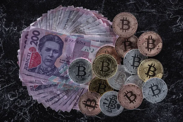 Вид сверху на груду различных биткоинов на гривневых банкнотах на мраморном столе — стоковое фото