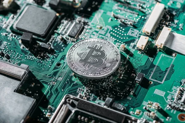 Close up view of silver bitcoin on computer motherboard — Stock Photo