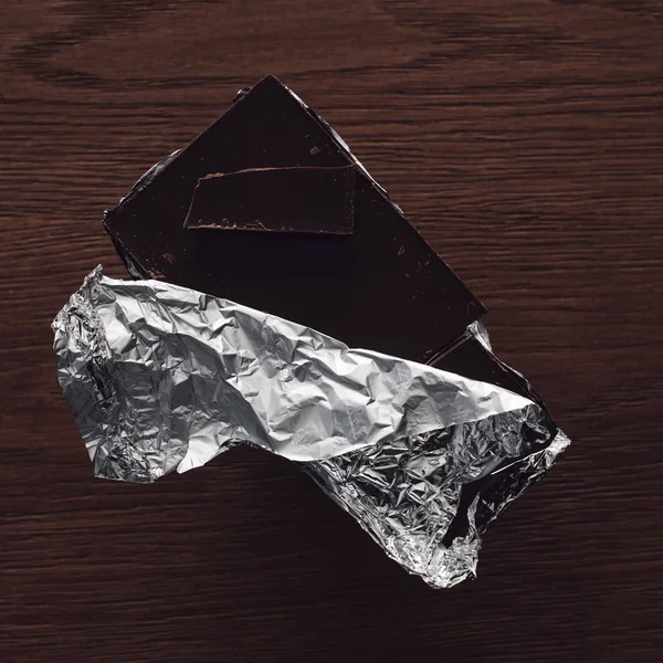 Top view of dark chocolate in foil on wooden tabletop — Stock Photo