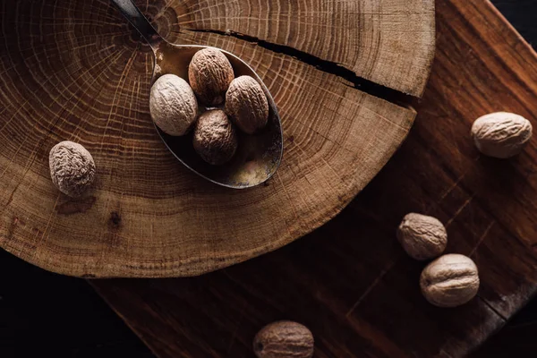 Elevated view of cutting board and spoon with pile of nutmegs on wooden tabletop — Stock Photo