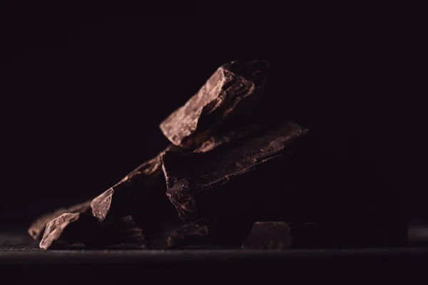 Close up view of pieces of dark chocolate on black background — Stock Photo