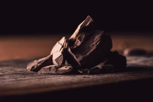 Closeup shot of pieces of dark chocolate on wooden tabletop — Stock Photo