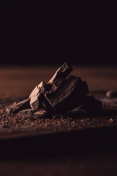 Close up shot of grated dark chocolate and pieces of chocolate on wooden table — Stock Photo