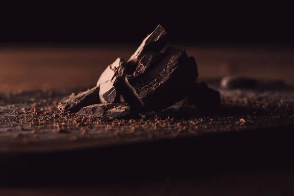 Closeup view of grated chocolate and pieces of chocolate on wooden table — Stock Photo