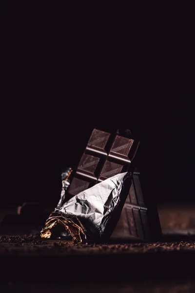 Vista de perto de duas barras de chocolate dispostas na mesa de madeira no fundo preto — Fotografia de Stock