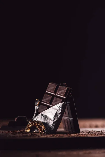 Primo piano di due tavolette di cioccolato disposte su tavolo di legno su sfondo nero — Foto stock