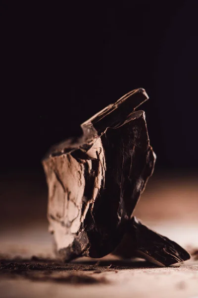 Closeup image of aranged pieces of dark chocolate on wooden table on black background — Stock Photo