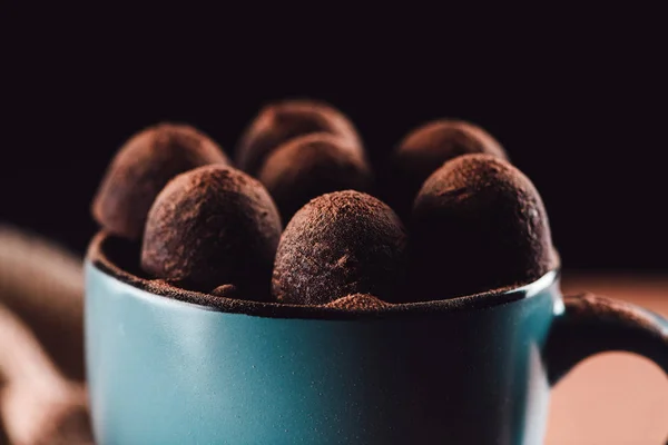 Primer plano tiro de trufas en taza de café sobre fondo negro - foto de stock