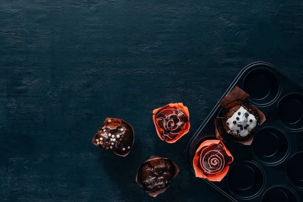 Draufsicht auf leckere Muffins mit Glasur in Backform auf Holzgrund — Stockfoto