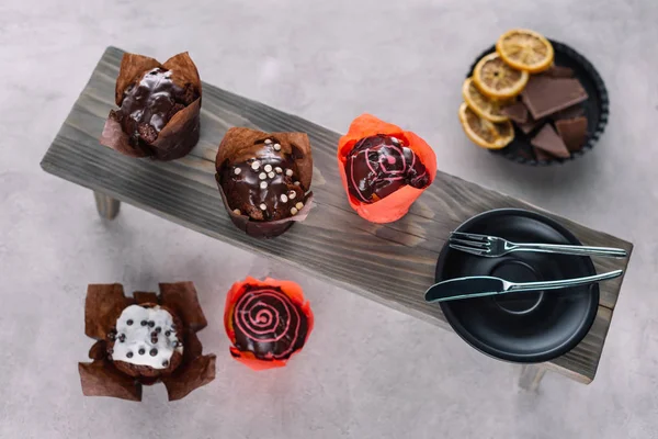 Sweet chocolate muffins and cutlery on wooden background — Stock Photo