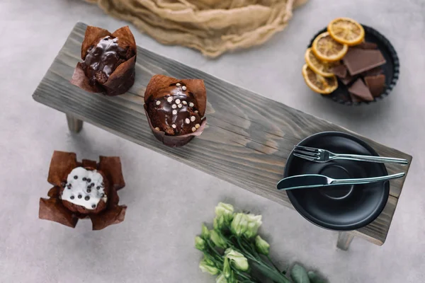 Солодкі кекси з шоколадними чіпсами та столовими приборами на дерев'яному фоні — Stock Photo
