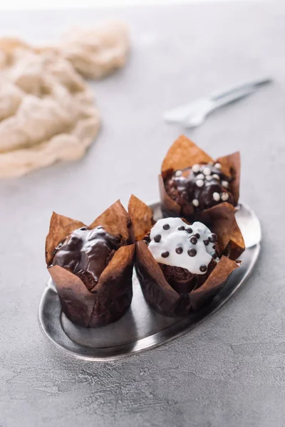 Süße Muffins mit Zuckerguss und Schokoladenchips auf Silbertablett serviert — Stockfoto