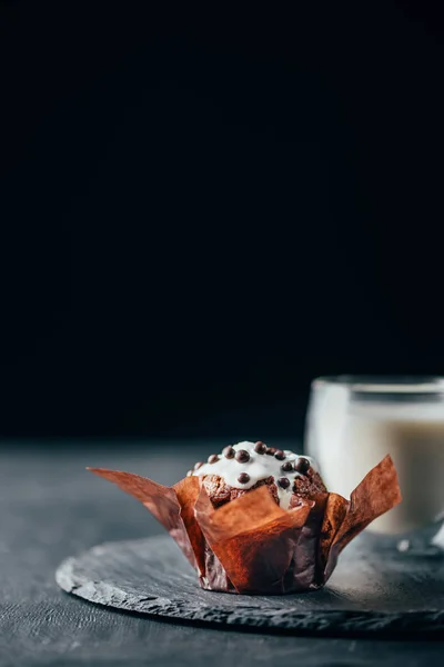 Muffin dolce con gocce di cioccolato e bicchiere di latte su lavagna — Foto stock