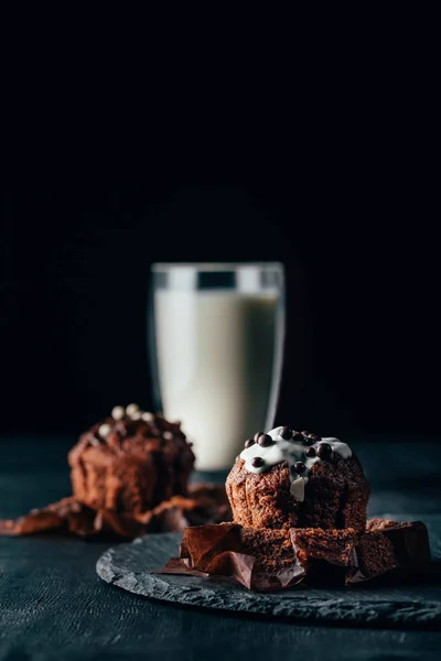 Süße Schokoladenmuffins und ein Glas Milch auf dunklem Hintergrund — Stockfoto