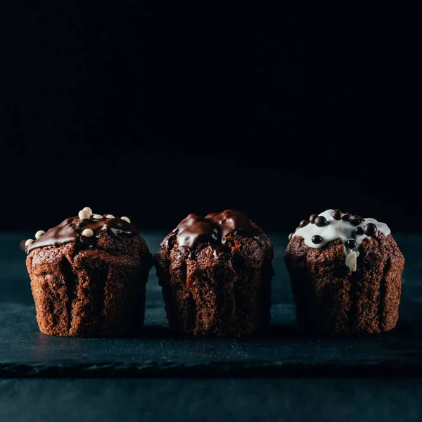 Muffins sucrés avec pépites de chocolat sur fond sombre — Photo de stock