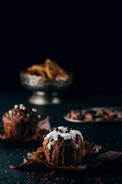 Sweet cupcakes with chocolate chips and sweet glaze on dark background — Stock Photo