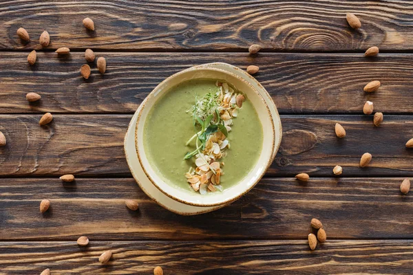 Vue du dessus de la soupe à la crème végétarienne avec brocoli et germes et amandes disposées sur le dessus de table en bois — Photo de stock